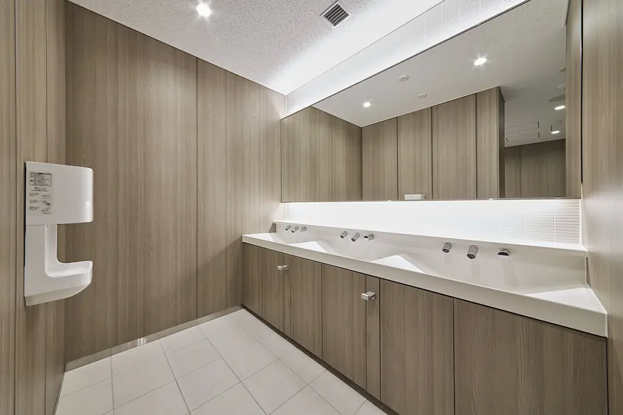 A minimalist bathroom with white floor and sinks, and wood textured brown walls